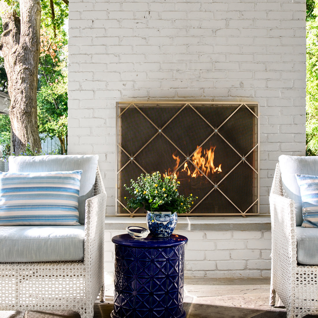 Celeste fireplace screen glowing against white brick, featuring star-inspired metalwork and artisan craftsmanship.