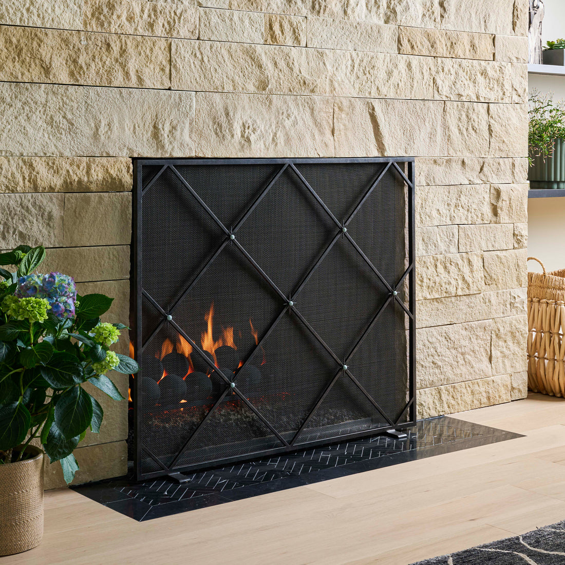Black Celeste fireplace screen with star accents adds handcrafted elegance to a stone hearth.