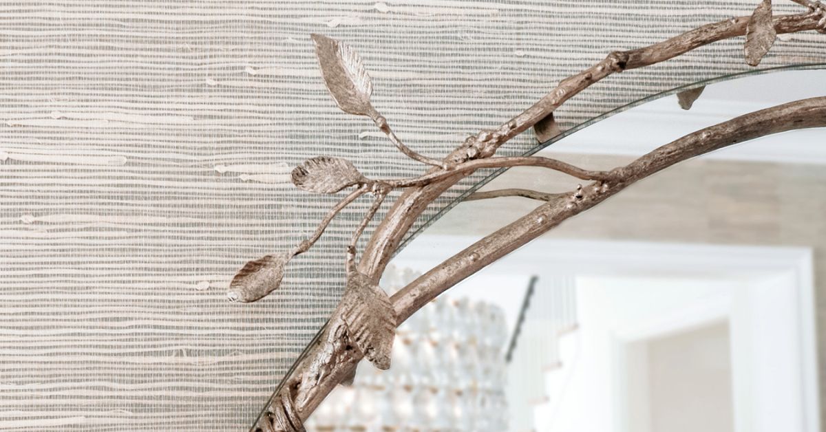 Metal-framed wall mirror positioned to extend light through an interior