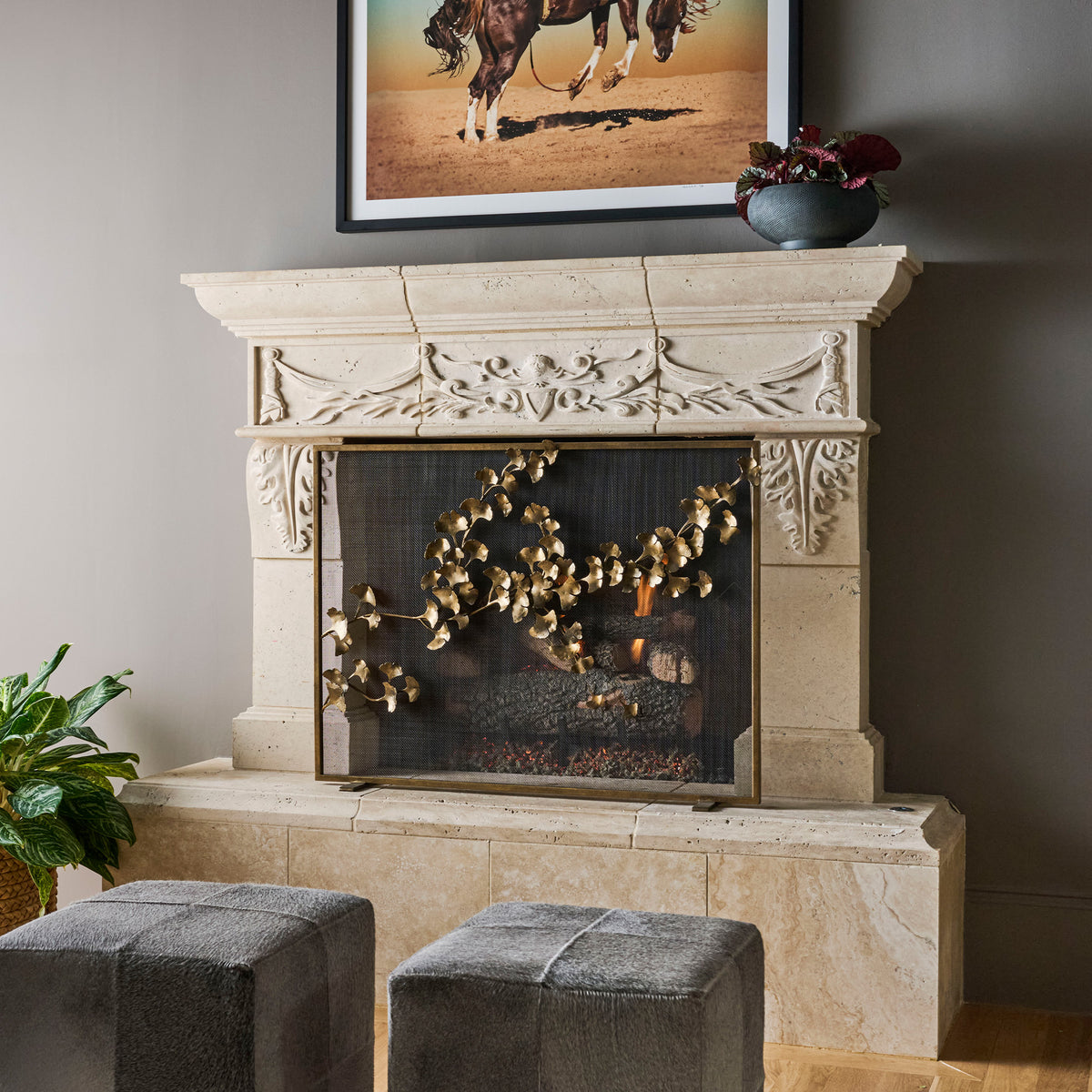 Ginkgo fireplace screen with hand-formed leaves installed in a carved stone fireplace