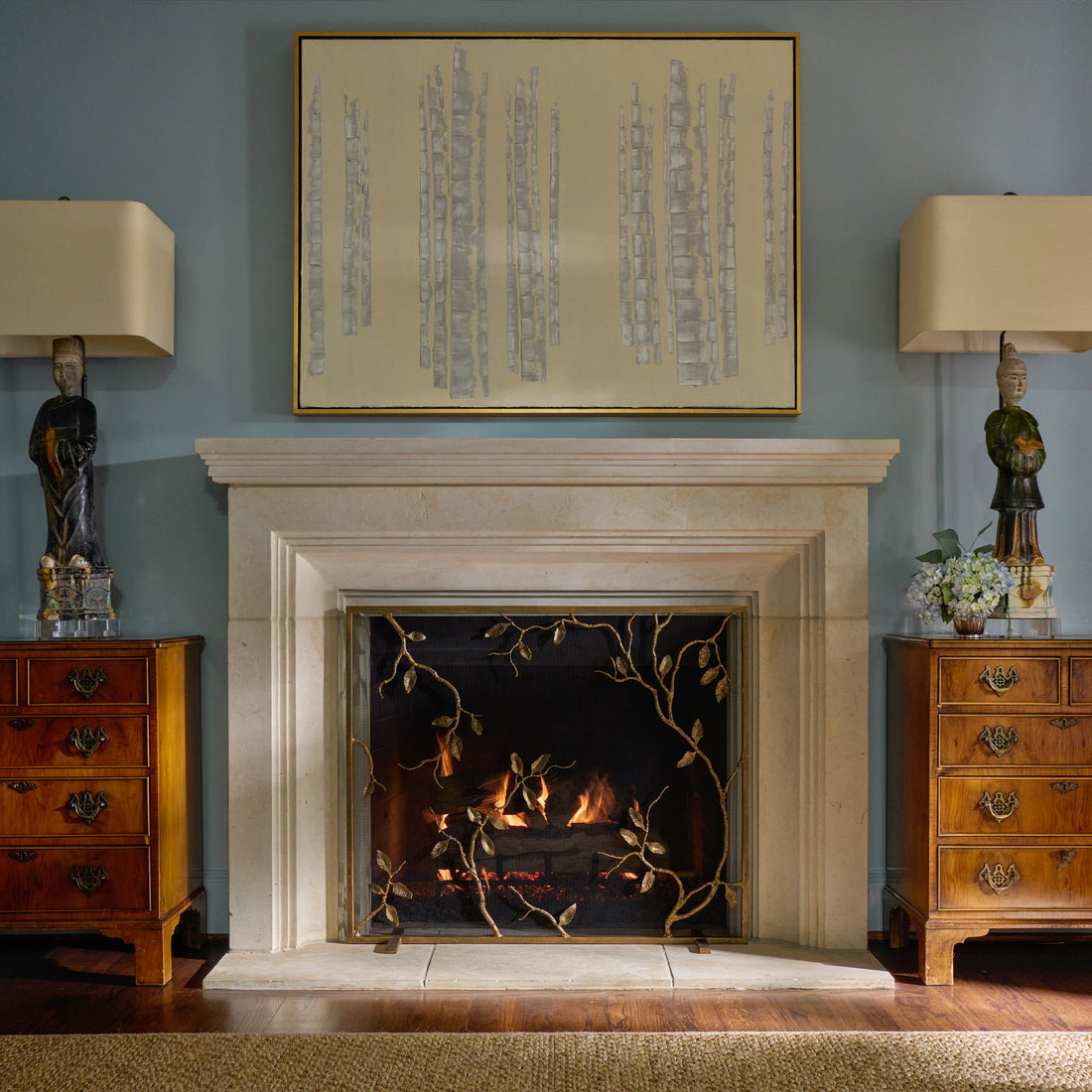 Custom fireplace screen featuring metal detail by Claire Crowe Collection. Above the fireplace mantel sits a decorative art decor piece and side tables on each side.