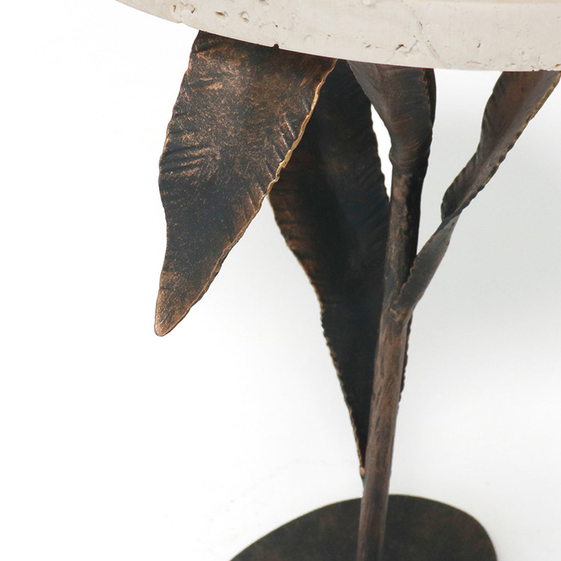 A close up of an iron tripod table base with leaf designs on the willow accent table, showing detailed craftsmanship and texture by Claire Crowe Collection.
